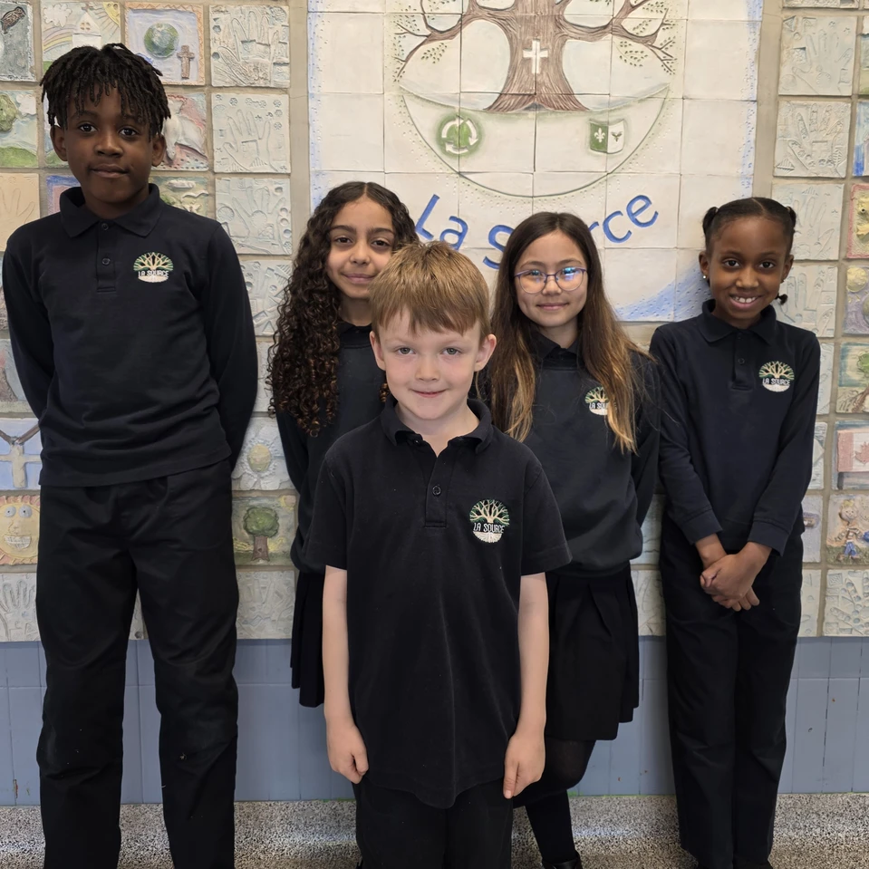 5 élèves de l'École la Source posent pour une photo devant un mur de l'école.
