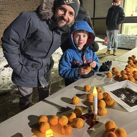 un adulte avec un élève devant une table pleine d'oranges